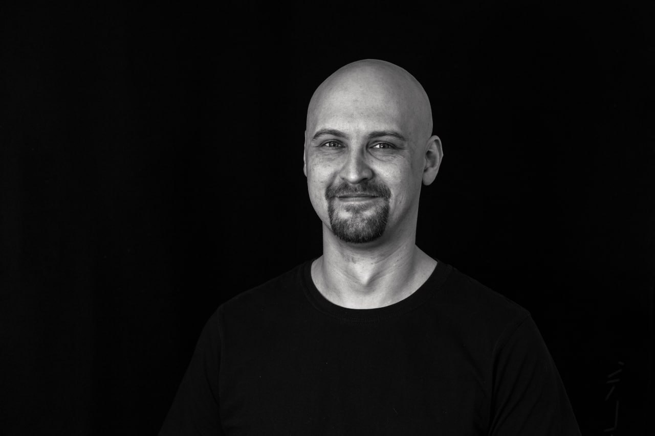 Сергей Кауров улыбается на черном фоне